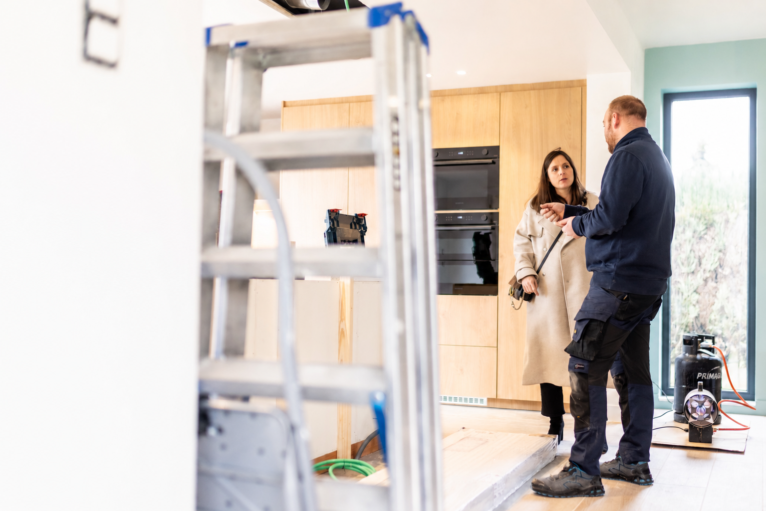 Laura en visite de chantier, échangeant avec un artisan dans une cuisine en cours d'installation